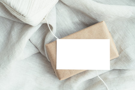 blank card mockup, business card, place card, ift tag, price tag, message card, Gift box wrapped in brown craft paper, wrapped in craft paper and tied with twine.の写真素材
