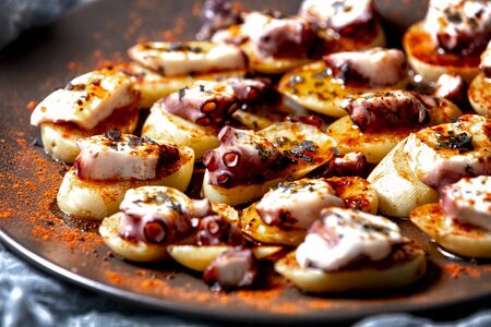 Octopus cooked Galician style, with potatoes and red pepper. Typical Spanish food dish, close-up view.の写真素材