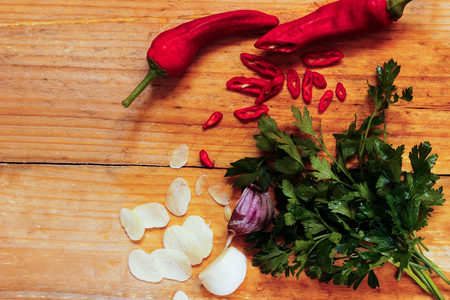 Chili, garlic, parsley greens on a wooden surface, top viewの写真素材