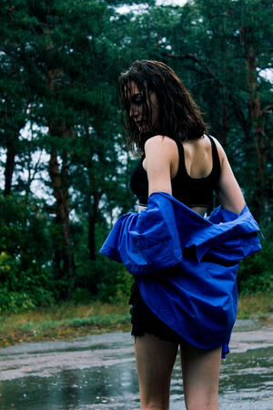 Girl in a blue shirt in the rain amid the wet asphaltの写真素材