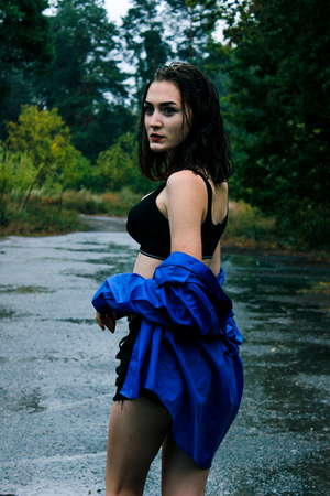 Girl in a blue shirt in the rain amid the wet asphaltの写真素材