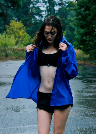 Girl in a blue shirt in the rain amid the wet asphaltの写真素材