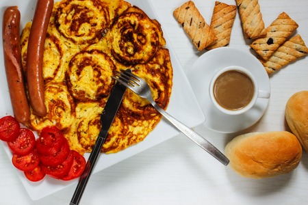 Breakfast of an omelette with sausages and coffee on a white wooden backgroundの写真素材