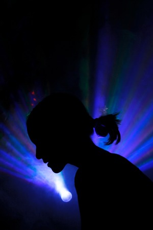 the silhouette of a person in disco background. color lasers in smoke. Side viewの写真素材