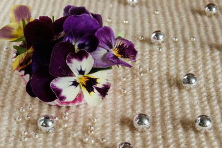 Still life with a pansy, a bouquet of flowers tied with ribbon and strewn with beadsの写真素材