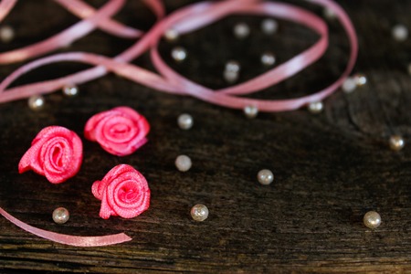Valentine's day greeting card. pink ribbons, beads, hearts and little pink roses on a dark treeの写真素材