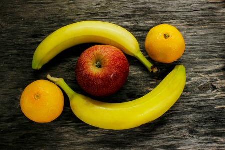 Fruit platter of resh mandarins and red apple and bananas on gray wooden table view from aboveの写真素材
