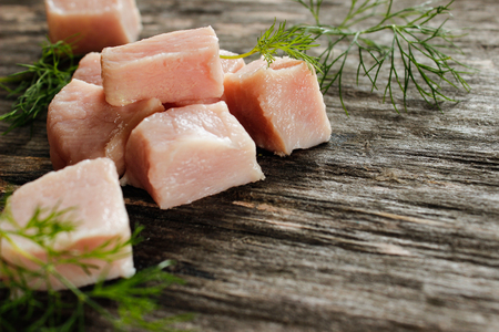 raw chicken fillet cut into cubes with green dill on a wooden surfaceの写真素材