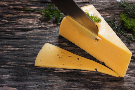 Hard cheese on a wooden table. Dairy products and agriculture. Close-up. Side viewの写真素材