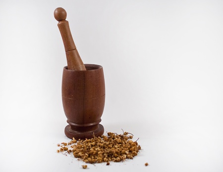 Mortar and pestle with dried herbs on a white background.の写真素材