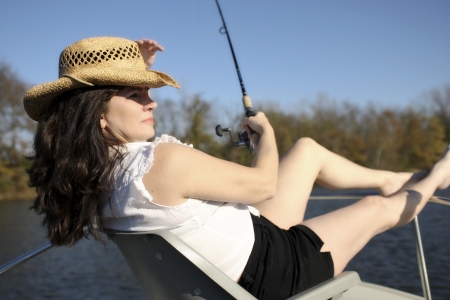 A mature woman enjoys the day while fishing on a boat.の写真素材