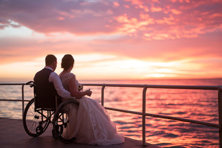 Wedding couple in a wheelchair on the background of the sea.の素材