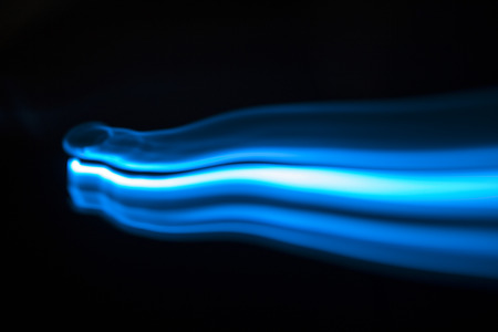 Blue and white streaks of light over black background with copy space for concept about natural gasの写真素材