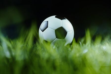Traditional football on an illuminated empty sports field at night backlit by bright spotlights in a...