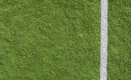 White line marking on green turf of a sports field viewed from above as a lower border with...