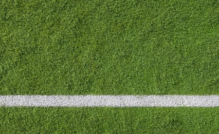 White line marking on green turf of a sports field viewed from above as a lower border with background copy spaceの写真素材
