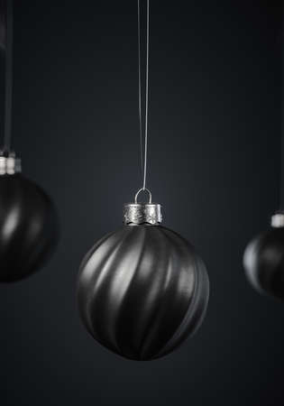 Three twisted striped black Christmas balls against dark gray background. Christmas decoration, festive atmosphere concept. Selective focus, portrait orientation.の写真素材