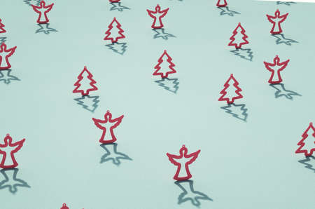 Rows of flat red matt Christmas ornaments over retro cyan surface. Mix of angel and conifer tree contours. Christmas theme background.の写真素材