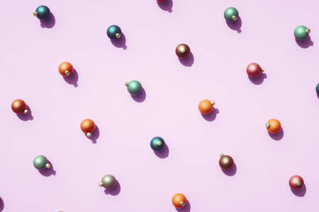 Rows of various color Christmas balls against retro pink surface. Top view pattern for Christmas...