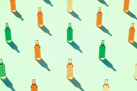 Rows of various color glass bottles against light blue / green surface. Mockups of full glass bottles without label, shadows on background. Retro drink bottle concept.の写真素材