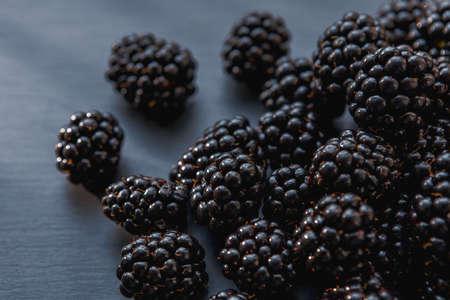 Close-up view on juicy and tasty blackberry fruits laying on gray table. Selective focus. Vitamins in fresh fruits concept.の写真素材
