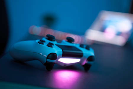 Gaming controller laying on table. Close-up of gamepad in low light room. Selective focus. Professional computer game playing, esport business and online world concept.の写真素材