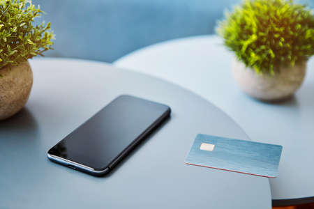 Mobile phone and electronic chip card laying on the round table. Modern technology, wireless device and transfer of energy concept.の写真素材