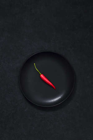 Group of red hot spicy vegetables. High angle view of chilli peppers on dark black background. Spicy ingredients in kitchen. Fresh and dry.の写真素材