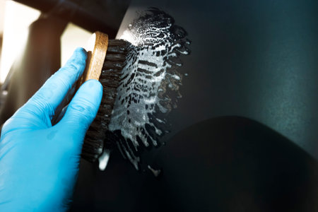 Closeup View Captures the Meticulous Process of Cleaning a Car's Surface. A Gloved Hand Scrubs With...