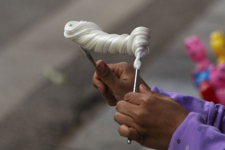 Close-up of woman twisting taffy-like confection on metal chopsticksの写真素材