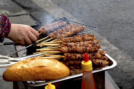Street vendor cooking meat on skewersの写真素材