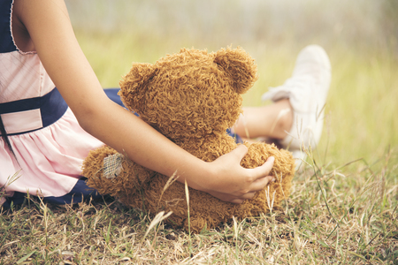 little girl hugging a fluffy teddy bearの写真素材