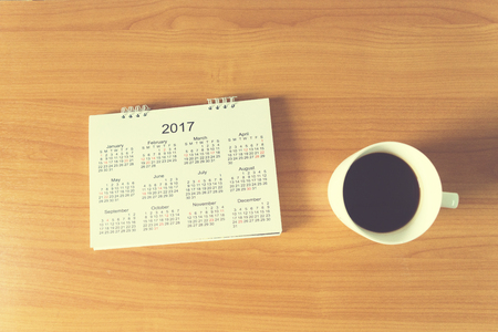 Travel Planning on Calendar and use post-it for note with a cup of coffee on a wooden tableの写真素材