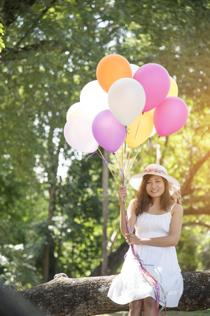 summer holidays, celebration and lifestyle concept - beautiful woman with colorful balloons outdoor in the park.の写真素材