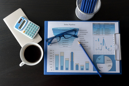 Business stuff, Graph, charts, calculator, glasses , pen and a cup of coffee.の写真素材