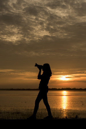 Silhouette Handsome Photographer take a photo with professional camera on the sunset.の写真素材
