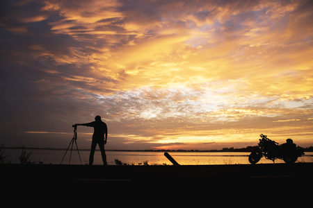 Silhouette Handsome Photographer take a photo with professional camera on the sunset.の写真素材