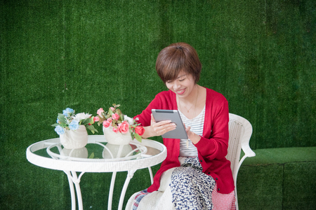 Chinese Businesswoman Working On Tablet Computer Outside Office. Beutiful Woman Wear Red Shirt Working outdoor.の写真素材