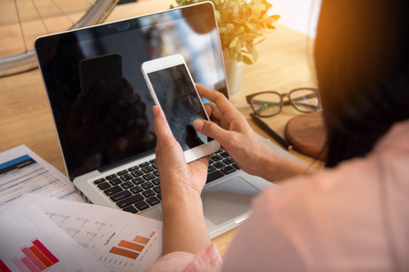 Beautiful business working woman using while working with laptop and reading report , graphs ,...