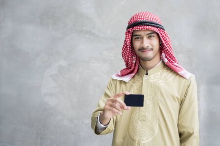 smiling handsome arabian man holding business card.の写真素材