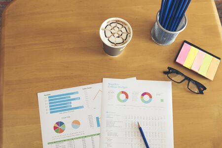 Business stuff, Graph, charts, calculator, glasses, pen and a cup of coffee.の写真素材