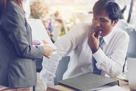 Asian Businessman thinking profit and loss about new project. Young secretary showing financial report.の写真素材