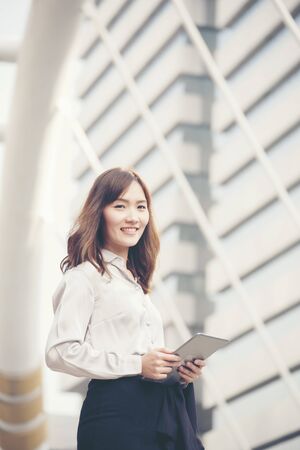 Young beautiful working woman holding smart tablet in the city.の写真素材