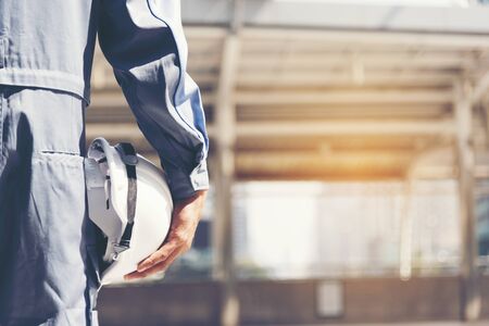 Construction engineer in Safety Suit Trust Team Holding White Yellow Safety hard hat Security Equipment on Construction Site. Hardhat Protect Head for Civil Construction Engineer. Engineering Conceptの写真素材