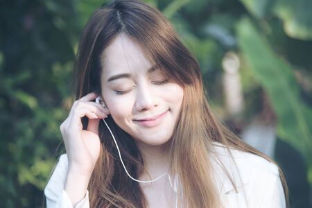 Beautiful woman listen to music from her smart phone relaxation in the parkの写真素材