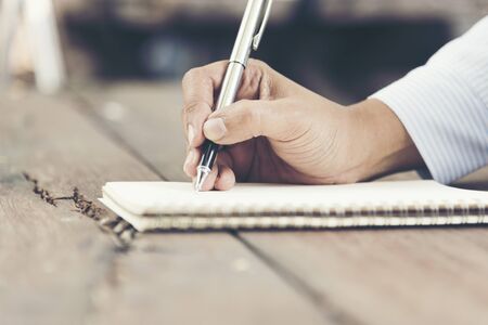 Woman writing on note paper diary on wooden table.の写真素材