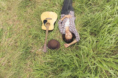 Top view of woman lay down on meadow with guitar instrument.の写真素材