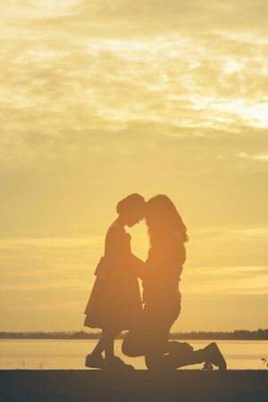 Silhouette woman holding air balloons standing and see the lake on the sunsetの写真素材