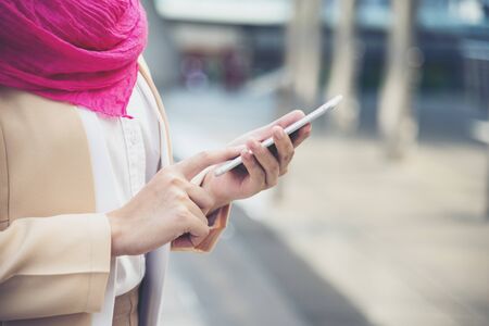 Islamic woman using smartphones app organize schedule agenda  focus on hands holding smartphone muslim modern uae city. Arab woman wear hijab and muslim formal dress sending text sms online lifestyleの写真素材