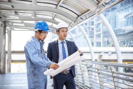Construction engineer in Safety Suit Trust Team Holding White Yellow Safety hard hat Security Equipment on Construction Site. Hardhat Protect Head for Civil Construction Engineer. Engineering Conceptの写真素材
